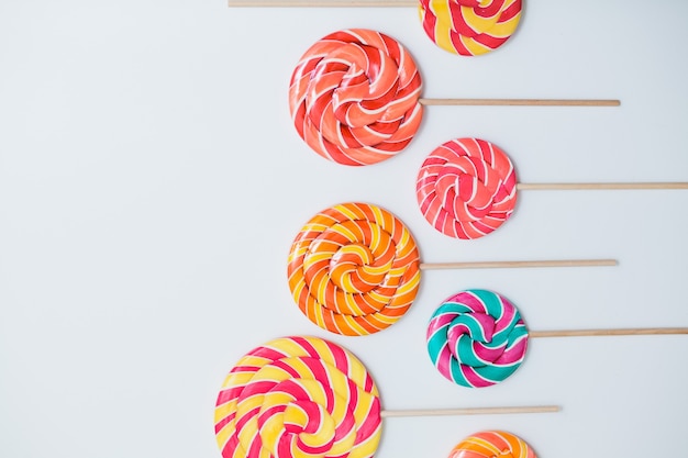 Amazing lollipops on sticks organised on white table.