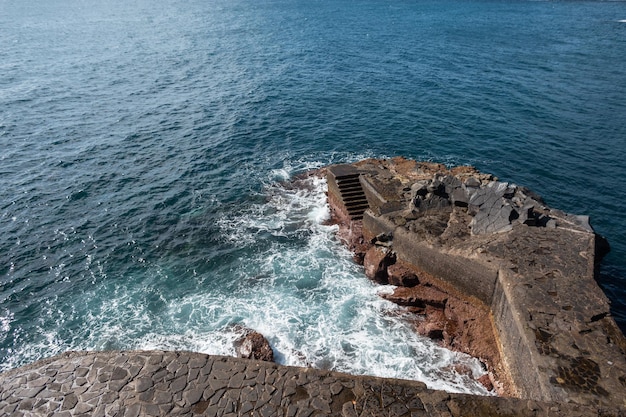 Amazing ocean with waves and rock with steps on the beautiful island of Madeira