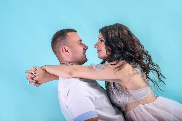 Amazing pregnant couple posing in studio against deep blue background, waiting for a baby