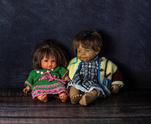 Photo amazing realistic two vintage porcelain dolls toys with blue and brown eyes the dolls are dressed in colorful knitted dresses couple