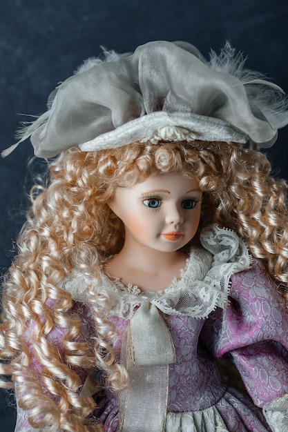 Amazing realistic vintage porcelain doll toy with blue eyes The doll dressed in a pink dress and has a blond hair Selective focus