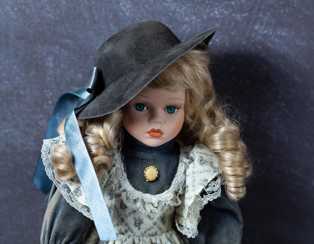 Photo amazing realistic vintage porcelain doll toy with blue eyes the doll dressed in a whiteblue dress with lace and has a blond hair selective focus