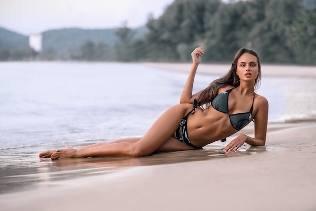 Amazing sensual seductive woman sitting and resting on the beach, enjoying summer holidays. 