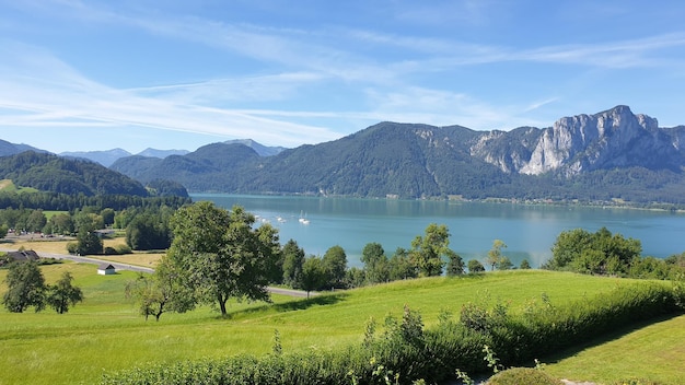 Amazing shot of the Lake Mondsee surrounded by forested landscapes against the blue sky in Austria