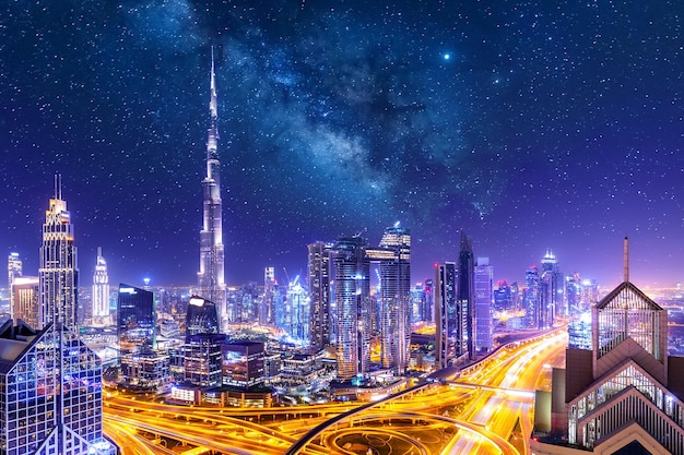 Incredibile paesaggio urbano dell'orizzonte con grattacieli illuminati. centro di dubai di notte con le stelle e la via lattea, emirati arabi uniti.