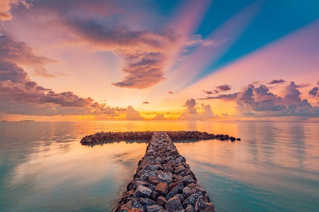 Amazing summer sunrise sunset with wave breaker. Stones rocks under sunset seascape skyline clouds