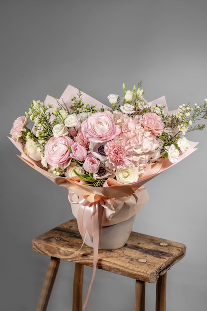 Amazing tender bouquet with pink ranunculus violet flowers and tiny white roses in cardboard box with pink ribbon Beautiful bunch of spring flowers Easter gift Seasonal spring flowers