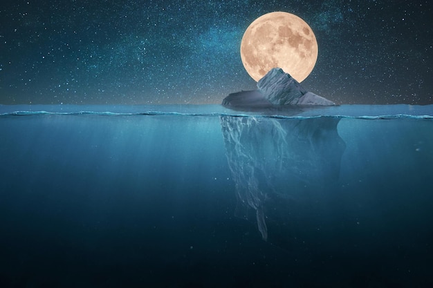 Amazing tip of the iceberg floats in the ocean at night with stars and full moon Hidden danger underwater Global warming creative idea Melting glaciers concept