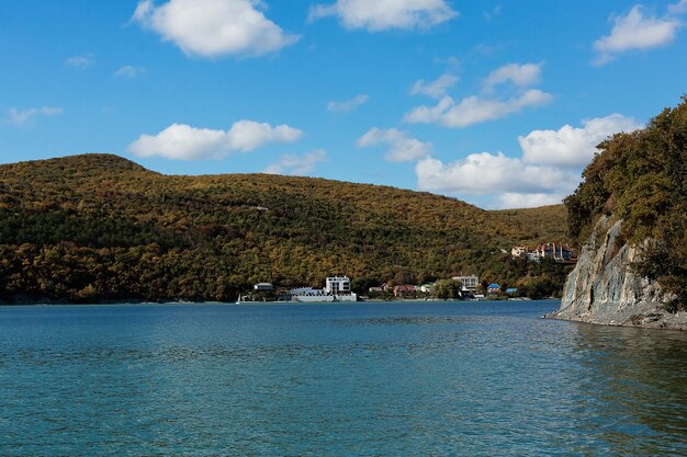 Photo amazing view of lake abrau durso among the colorful autumn forest picturesque wooded mountains and blue sky