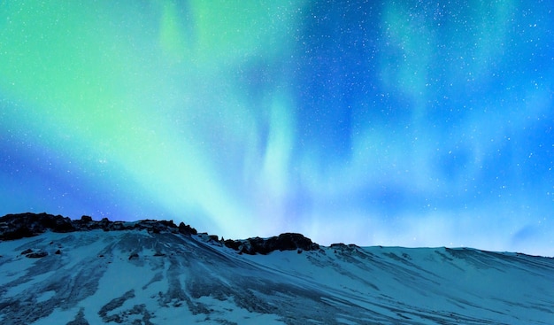 Foto una vista straordinaria sulla luce settentrionale e il paesaggio di alte montagne coperto dalle forze della natura innevate aurora borealis islanda