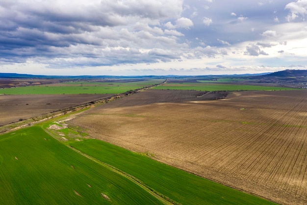 Amazing wide aerial view from drone of beautiful green countryside fields road and cloudy sky