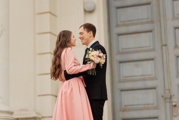 Amazing young attractive newly married couple walking and posing in the downtown with beautiful and ancient architecture