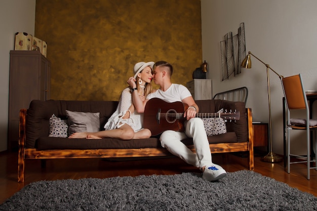 Photo amazing young couple with guitar in interior of room. cute woman and man on sofa with guitar