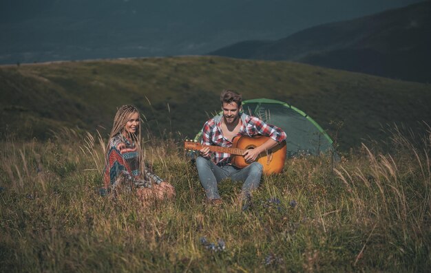 Amazing young loving couple on camp outside in free alternative vacation camping over mountains happ