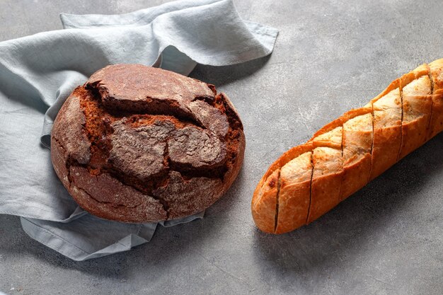 Ambachtelijk donker ongezuurd brood met geroosterd gesneden lookbrood baguette geserveerd op grijze stenen achtergrond bakkerij concept