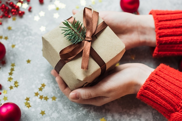 Ambachtelijk geschenk met een strik en een takje kerstboom omringd door confetti