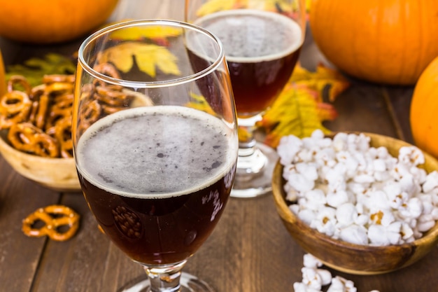 Ambachtelijk pompoenbier in bierglazen met zoute pretzels en popcorn.