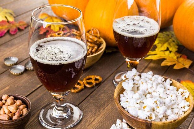 Ambachtelijk pompoenbier in bierglazen met zoute pretzels en popcorn.