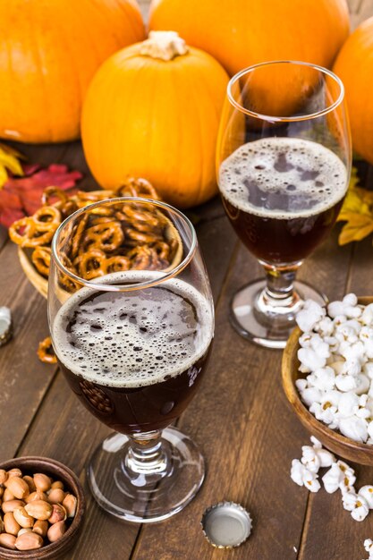 Ambachtelijk pompoenbier in bierglazen met zoute pretzels en popcorn.