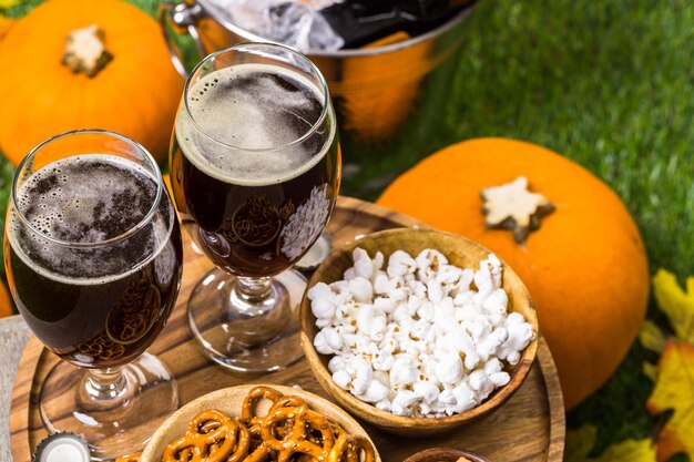 Ambachtelijk pompoenbier in bierglazen met zoute pretzels en popcorn.