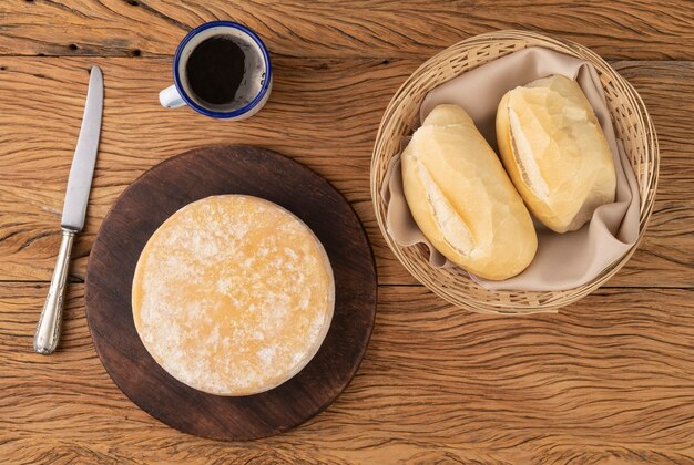 Ambachtelijke Canastra-kaas uit Minas Gerais, Brazilië met brood en koffiekopje over houten tafel.