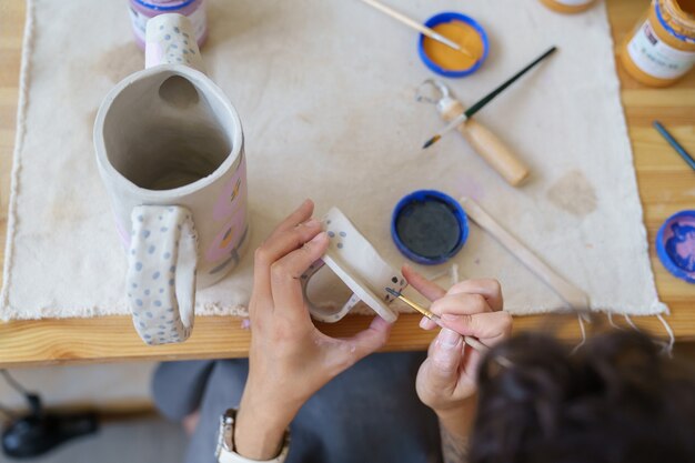 Ambachtelijke en kleine zakelijke kunstenaarsvrouw maakt aardewerk bij het fabricageproces van kunstlessen in de studio