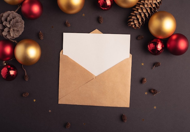 Ambachtelijke envelop met een blanco vel papier en kerstversiering op een donkere achtergrond