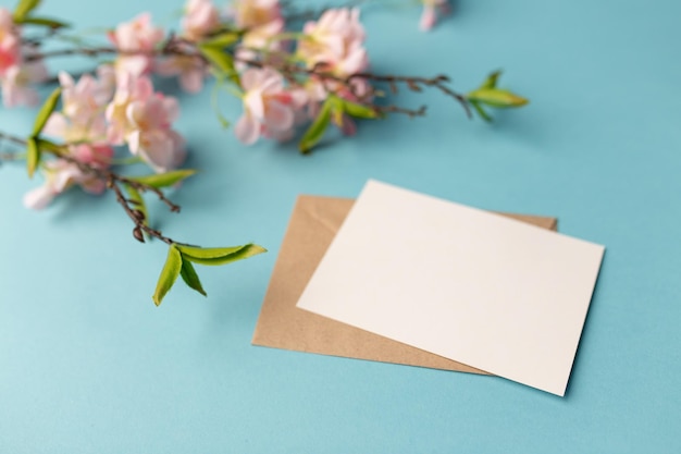 Ambachtelijke enveloppen wit blanco vel papier en een takje magnolia op een blauwe achtergrond