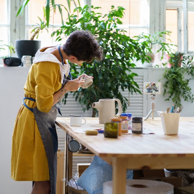 Ambachtelijke keramistvrouw neemt masterclass op voor aardewerk online videocursussen in workshop kruik maken