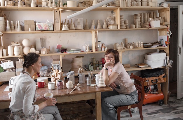 Ambachtelijke meisjes zitten aan een tafel in een werkplaats die houten speelgoed maakt