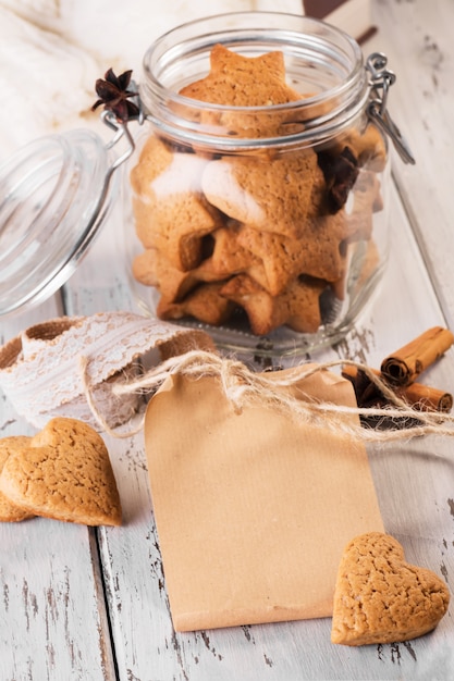 Ambachtelijke papieren notitie of wenskaart met gemberkoekjes gevormd als harten op een houten tafel.