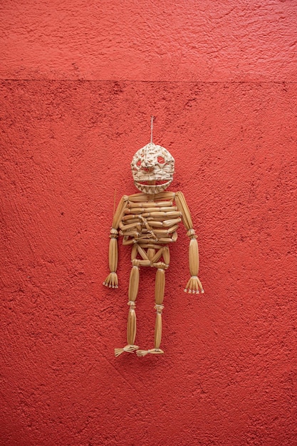 Ambachtelijke schedel gemaakt van stro, hangend aan de rode muur in de dag van de doden