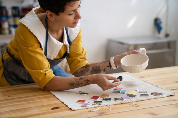 Ambachtelijke servies maken vrouw kunstenaar kiest verfkleur voor handgemaakte beker in studio voor online bestellingen