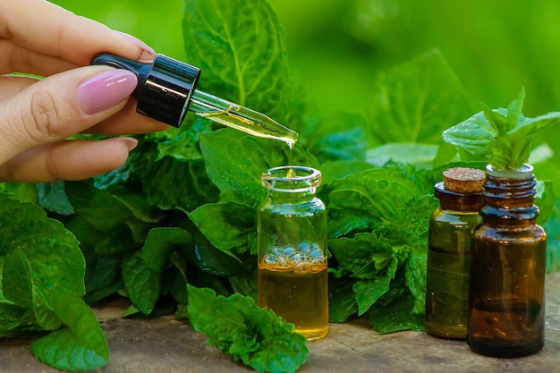 Photo amber bottle with essential oil peppermint with fresh mint leaves, herbal scent in a dark glass jar. aromatherapy concept. selective focus