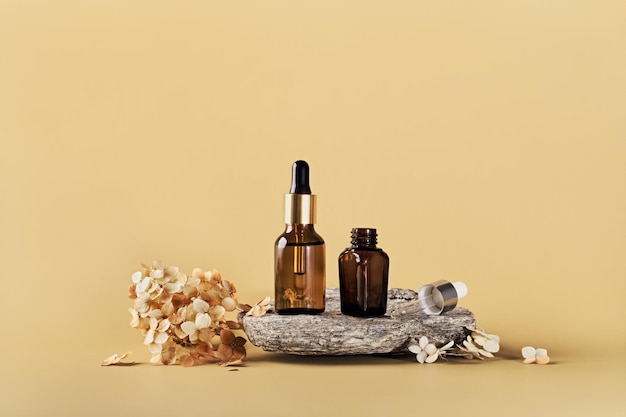 Amber glass bottles for branding mockup on stone podium and dried flowers Eco friendly skincare beauty product concept