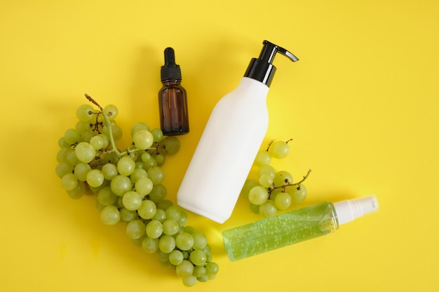 Amber glass droppe bottle and white mock up bottle and green grapes on yellow background