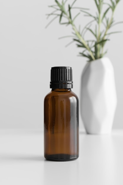 Amber glass essential oil bottle mockup with a rosemary on the white table