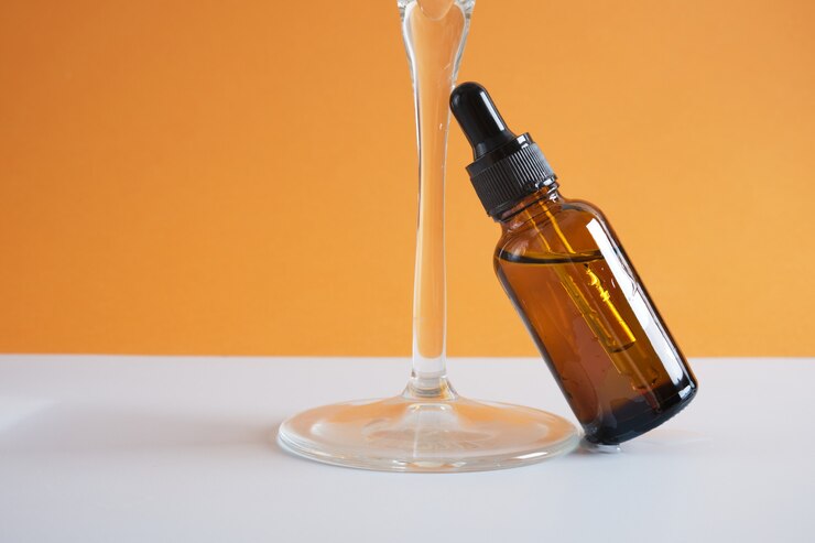 Amberglazen fles met een pipet en een glas water op een bruine achtergrond, een druppelflesje voor cosmetische olie of serum