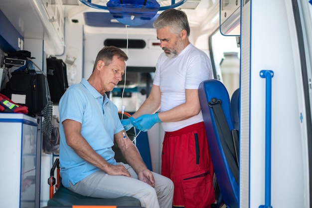 Photo ambulance doctor preparing the patient for an intravenous infusion procedure