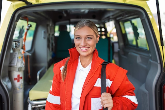 Ambulance staff member emerges from the back of an ambulance with her emergency backpack and vital signs monitor