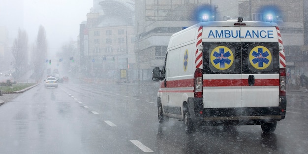 An ambulance took the patient to the clinic with the turn signals on. Bad weather outside, rain with wet snow.