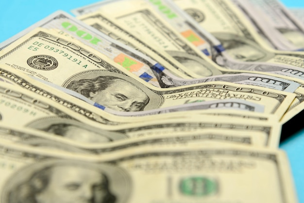 American 100 dollar bills laid out on a blue background