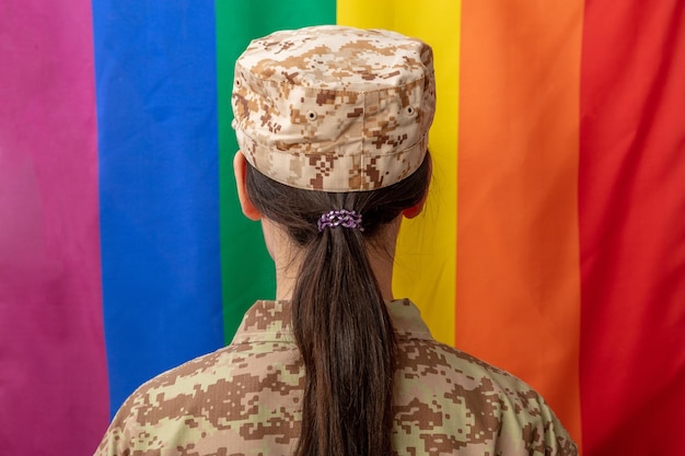 American army female soldier in USA military digital pattern uniform looking at lgbt flag