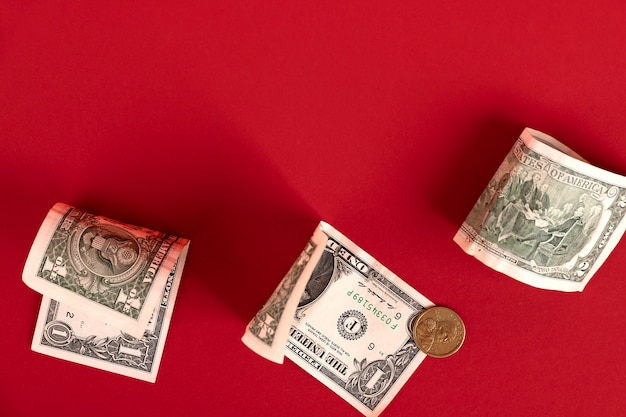 Photo american banknotes and coins are scattered over a red background. copy space.