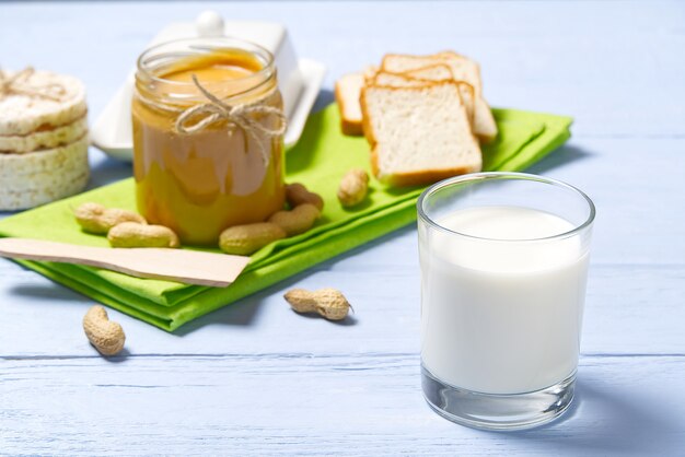 American breakfast with milk and peanut butter bread that are laying on the light blue wooden table