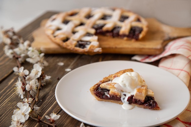 American cherry pie A piece of cake with a scoop of ice cream on a plate with a sprig of cherries