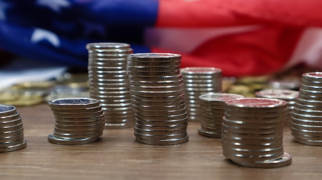 American coins with the flag of the United States of America. Investment concept, business finance and money saving. US coins stacked against the background of the American flag. Selective focus.