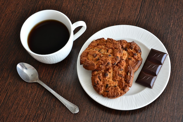 一杯のコーヒーと白い皿にチョコレートとアメリカン クッキー