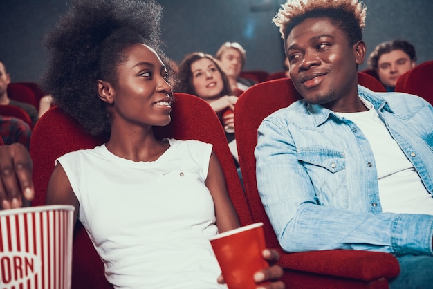 American couple with popcorn watching movie in cinema.