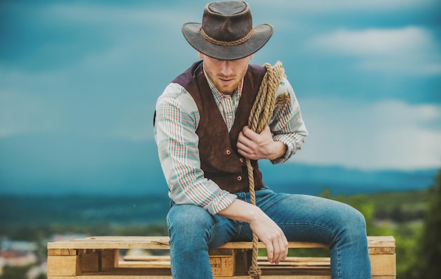 American cowboy man cowboy with lasso rope on sky background brutal western guy